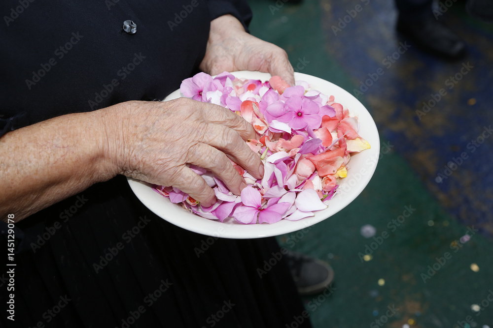 Foto Stock piatto tenuto da un amano da rompere in segno di buon augurio  per gli sposi con dentro riso e petali colorati | Adobe Stock