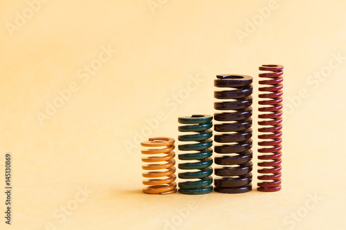 Iron spring set different hardness flexibility sizes. Colorful metallic spiral coil wires on yellow background.