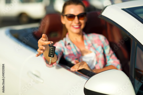 Young pretty woman sitting in a convertible car with the keys in hand