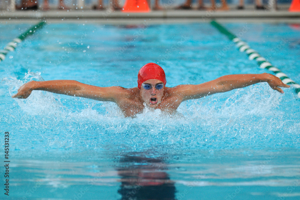 Male competitive swimmer swimming the butterfly stroke in a meet