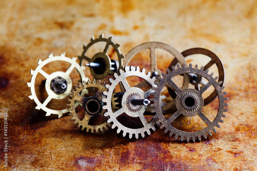 Antique clock mechanism steampunk style cogs gears wheels macro view. Vintage rusty metal surface background, shallow depth of field