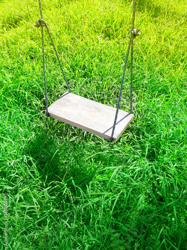 Obraz na płótnie An old wooden swing hanging in green garden, selective focus w salonie
