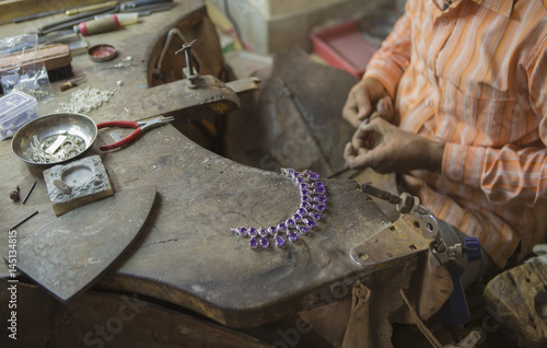 Indian Jeweler making an Oriental Jewelry in workshop. Handmade traditional jewel Manufacturing in Jaipur