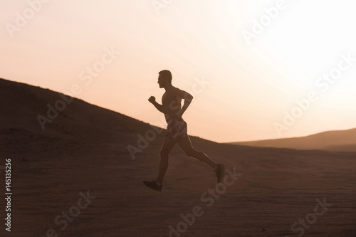 Fototapeta Naklejka Na Ścianę i Meble -  Man runner running in dune at sunset