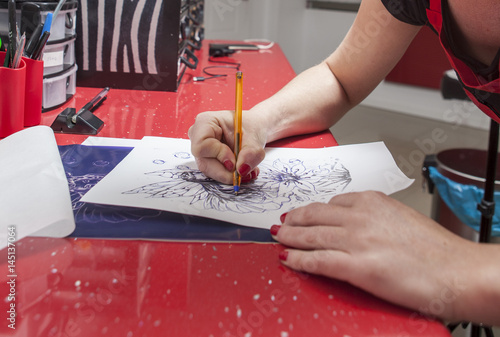 Tattooist woman tracing contours of sketch drawing