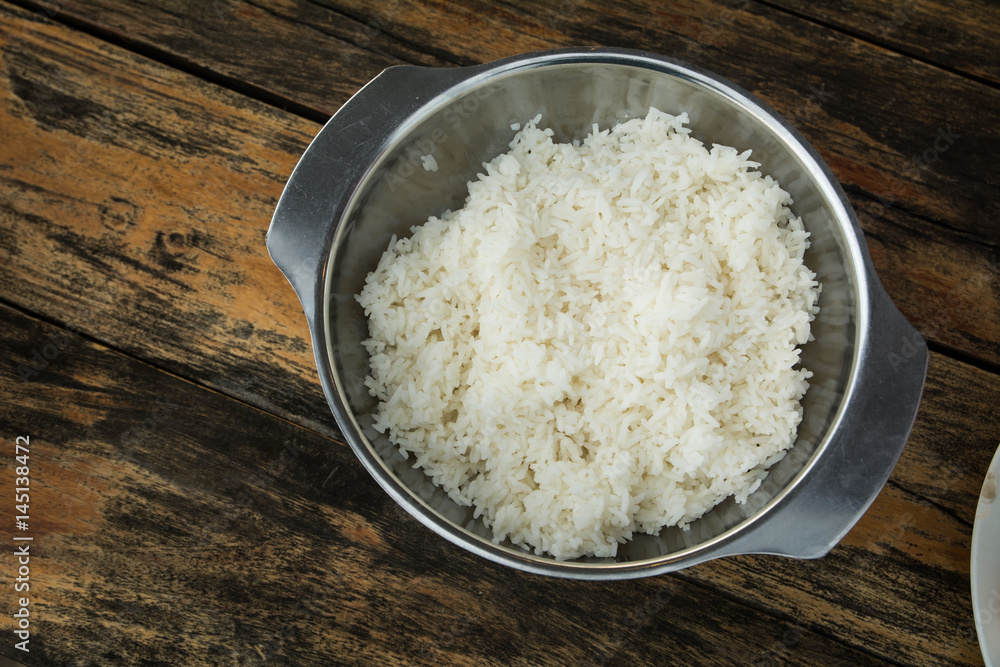 Cooked rice in pot on wooden table (wooden background)