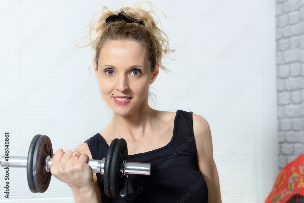 Portrait of young woman doing fitness exercise with dumbbells, at home Portrait of young woman doing fitness exercise with dumbbells, at home