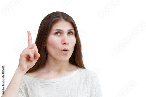 Portrait of a young woman in a light jumper with surprising expression on her face pointing up with finger isolated on white background. Demonstration of various emotions.
