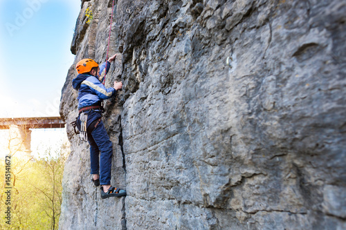 Kid rock climber climbs the cliff. © zhukovvvlad