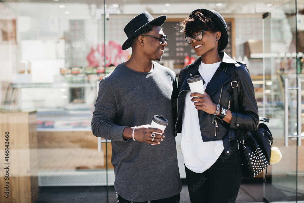 Stylish young african couple drinking coffee and walking a street of summer. Stylish young african couple drinking coffee and walking a street of summer.