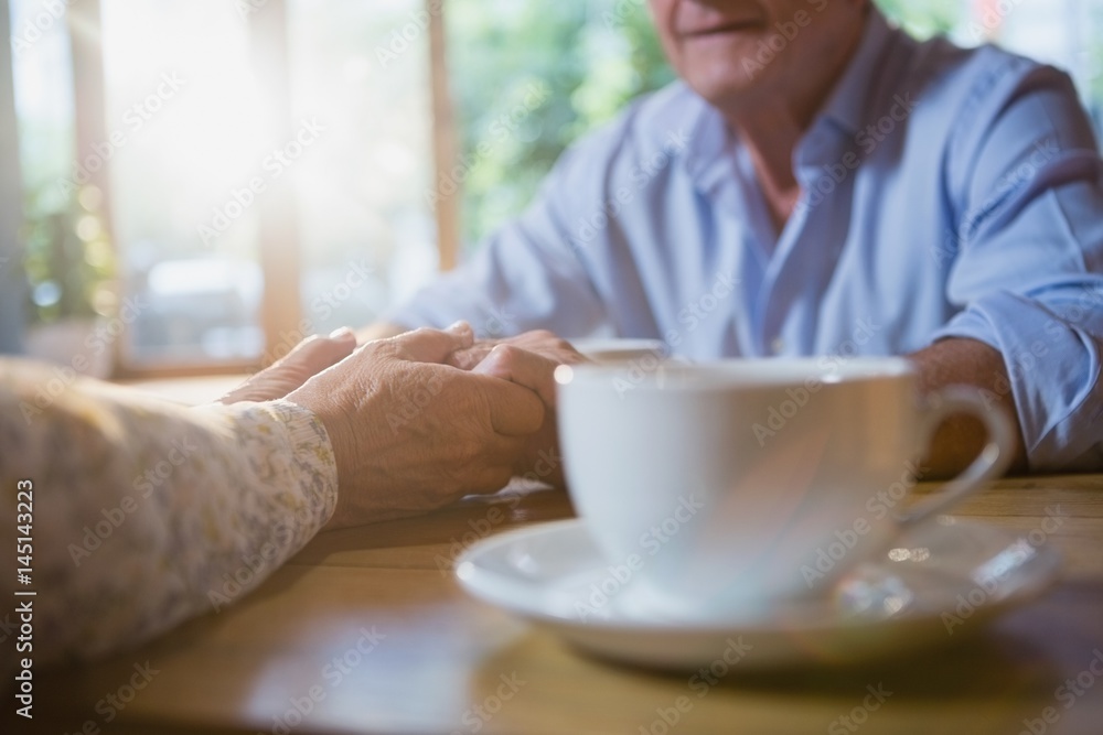 Senior couple holding hands while having coffee Senior couple holding hands while having coffee