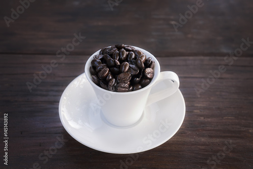 Coffee beans in cup on wooden background