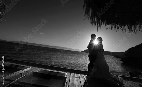 Silhouette di una coppia che si bacia al tramonto con il sole che crea una stella tra i due visi