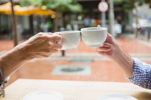 Billede på lærred Hands of senior couple toasting coffee cups