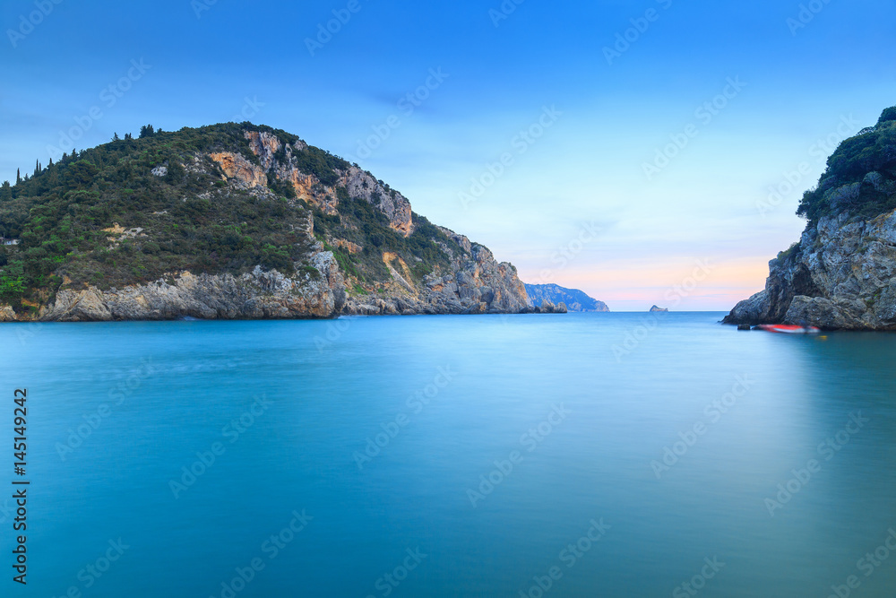 Fototapeta premium Long exposure landscape of Paleokastritsa famous sand beach in close bay on Corfu island at dusk, Ionian archipelago, Greece.