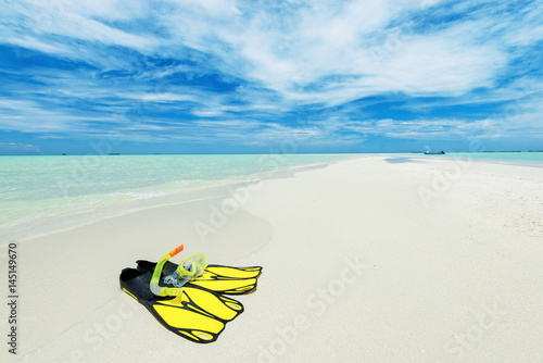 Fins and scuba mask on the white sand beach. Copy space.