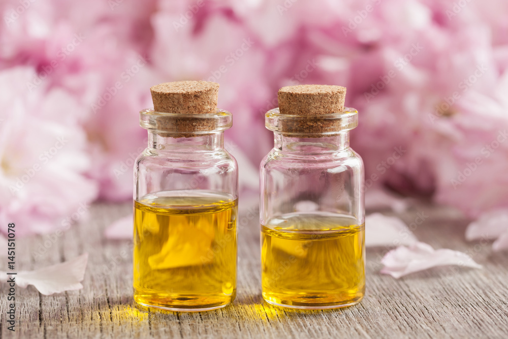 Two bottles of essential oil with pink cherry blossoms in the background