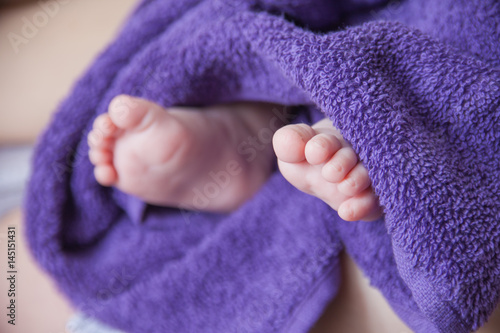 Baby feet folded in purple towel