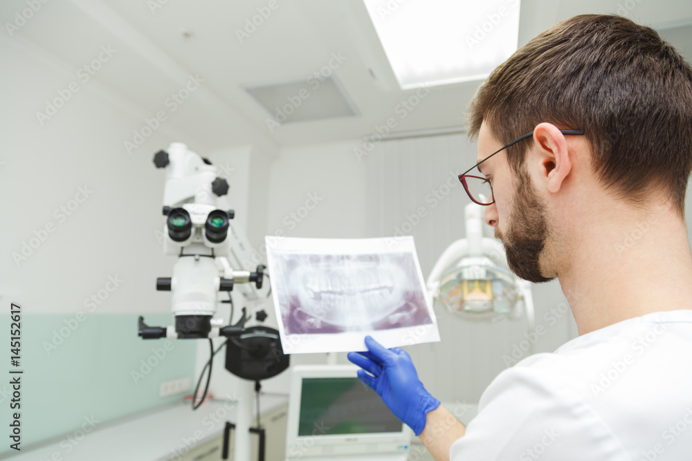Dentist looks at a snapshot of teeth Dentist looks at a snapshot of teeth