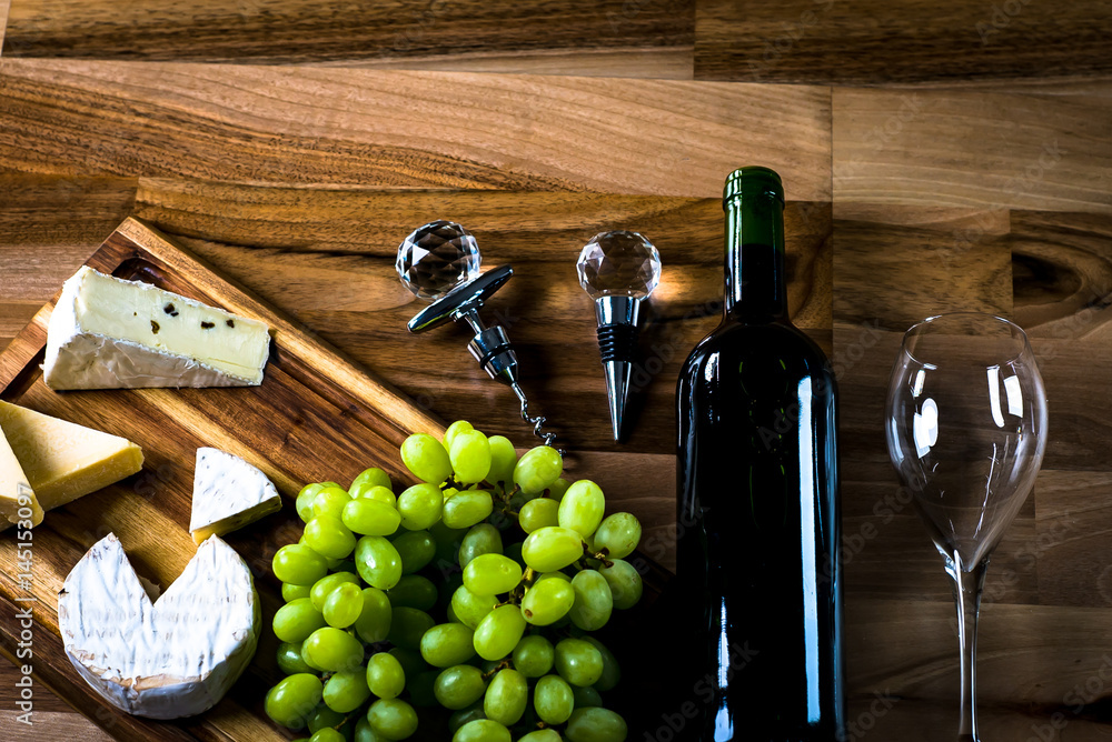 Obraz premium Wine bottles with grapes and cheese on wooden rustic background. copy space