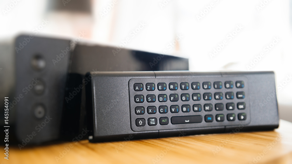 Full keyboard on small remote control next to wireless tv box used for TV  Internet Telephone communication via fiber optic or coaxial cable Stock  Photo | Adobe Stock