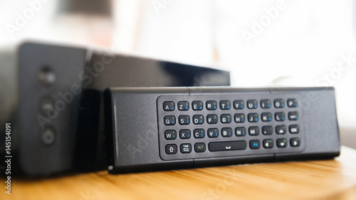 Full keyboard on small remote control next to wireless tv box used for TV Internet Telephone communication via fiber optic or coaxial cable  photo