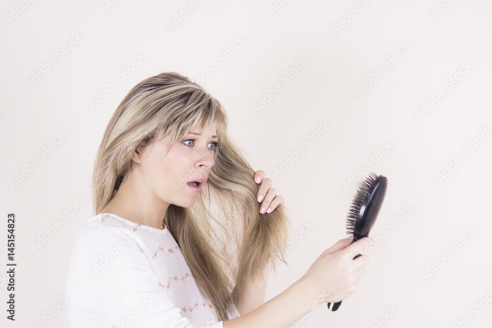 Hair loss. Depressed young woman looking at her hairbrush and expressing negativity Hair loss. Depressed young woman looking at her hairbrush and expressing negativity