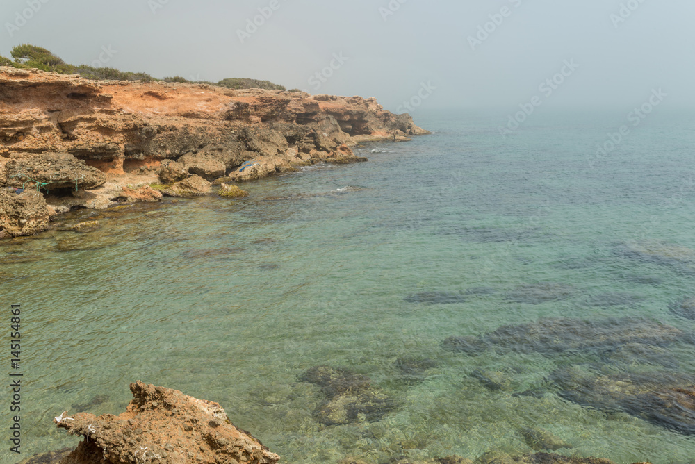 Fototapeta premium Acantilado del mar Mediterráneo con aguas cristalinas y bruma