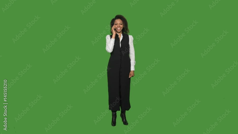 Young african business woman in formal suit answering and talking phone isolated on green background. Young african business woman in formal suit answering and talking phone isolated on green background.