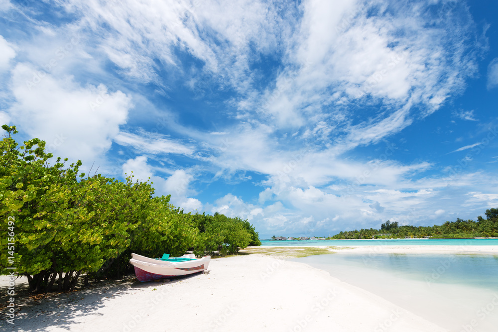 Wooden boat on the white sand beach.Maldives islands