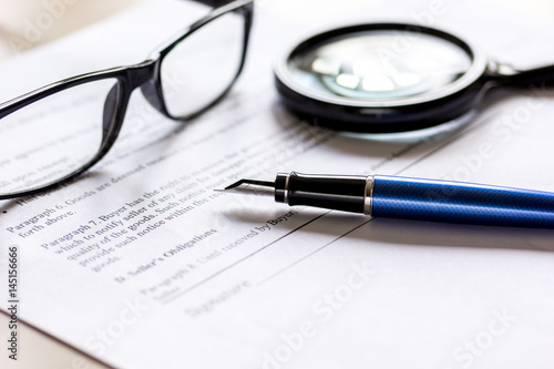 office desk with signing contract, glasses, magnifier and pen for business