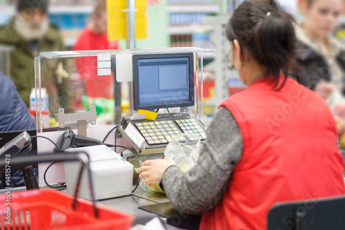 Cash desk with cashier serves customer in modern supermarket photo