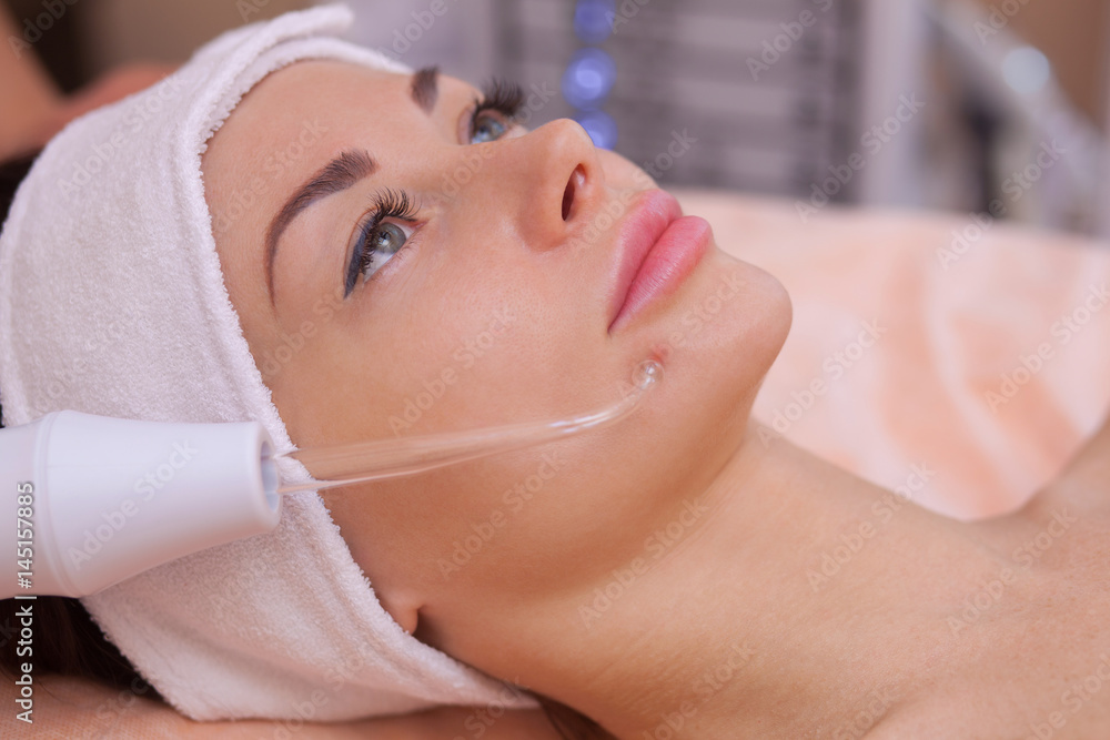 The doctor-cosmetologist makes the procedure Microcurrent therapy of the facial skin of a beautiful, young woman in a beauty salon.Cosmetology and professional skin care.