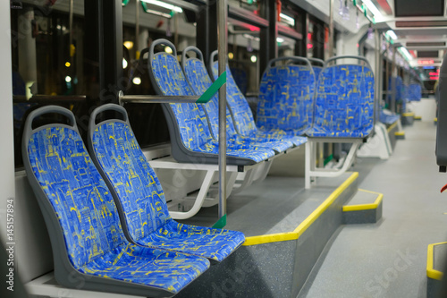 Interior of modern city low floor city tram with seats and hand grips in night
