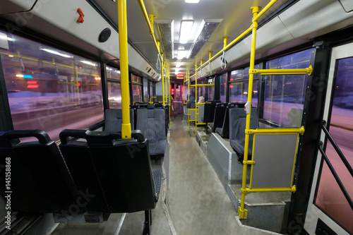 Interior of modern city trolley bus in back part with doors in night