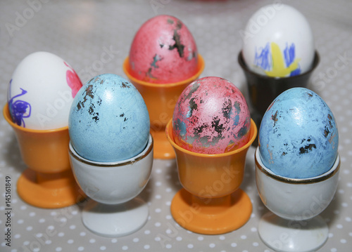 Målade ägg till påsk i olika färger sitter i äggkoppar