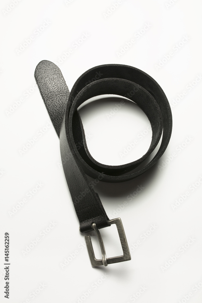 Black leather belt lying on a white background. Closeup shot Black leather belt lying on a white background. Closeup shot