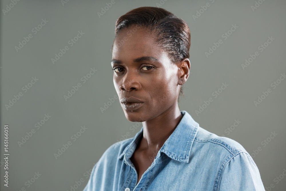 Obraz premium Androgynous man in denim shirt posing against grey background