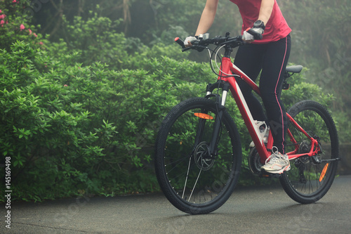 Young woman riding mountain bike on forest trail © lzf