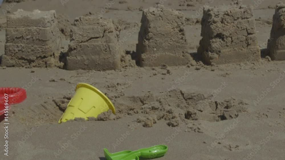 Digging Toys and Sandcastles Along the Ocean with Waves Crashing on the Beach Digging Toys and Sandcastles Along the Ocean with Waves Crashing on the Beach