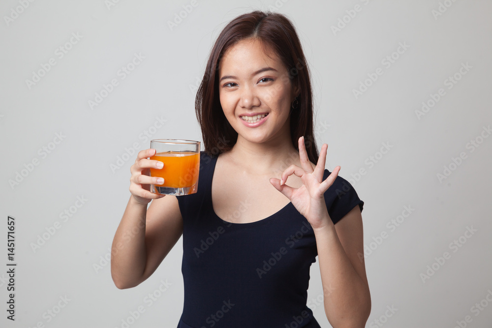 Young Asian woman drink orange juice show OK sign. Young Asian woman drink orange juice show OK sign.
