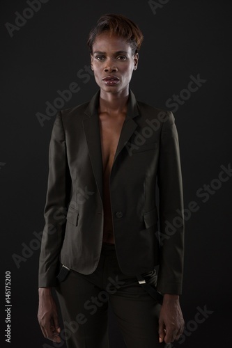 Androgynous man in suit posing against grey background