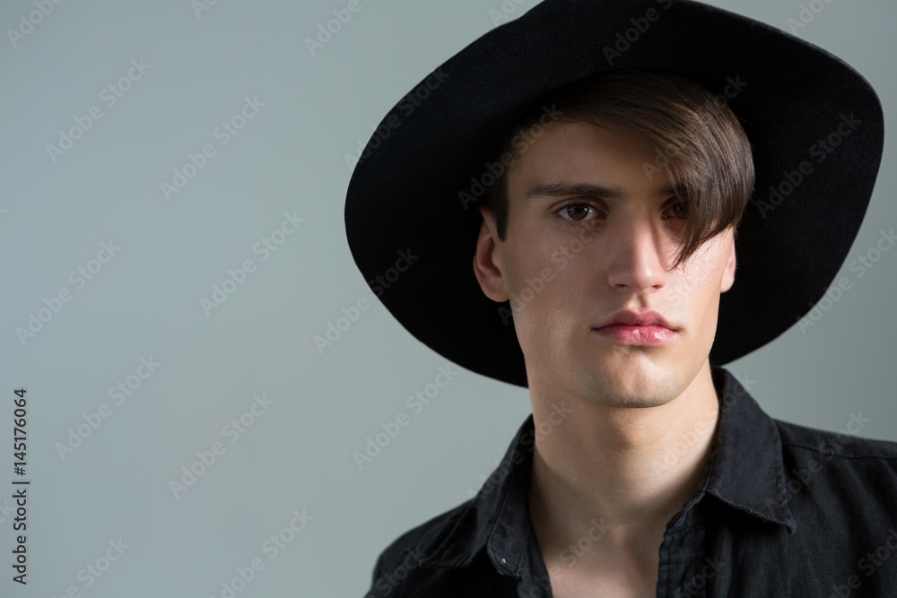 Androgynous man in hat posing against grey background Androgynous man in hat posing against grey background