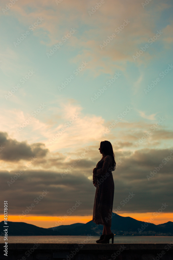 Silhouette of a pregnant woman at sunset by the sea Montenegro