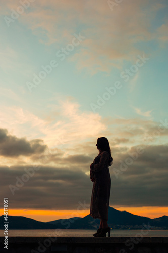 Silhouette of a pregnant woman at sunset by the sea Montenegro © Nadtochiy