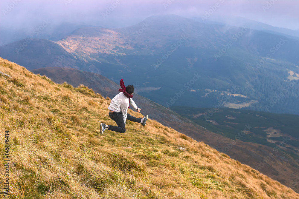 Man jumps at spring landscape in the Carpathian mountains