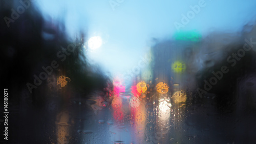 Rain drops on the car glass with traffic light and vintage filter blurred background