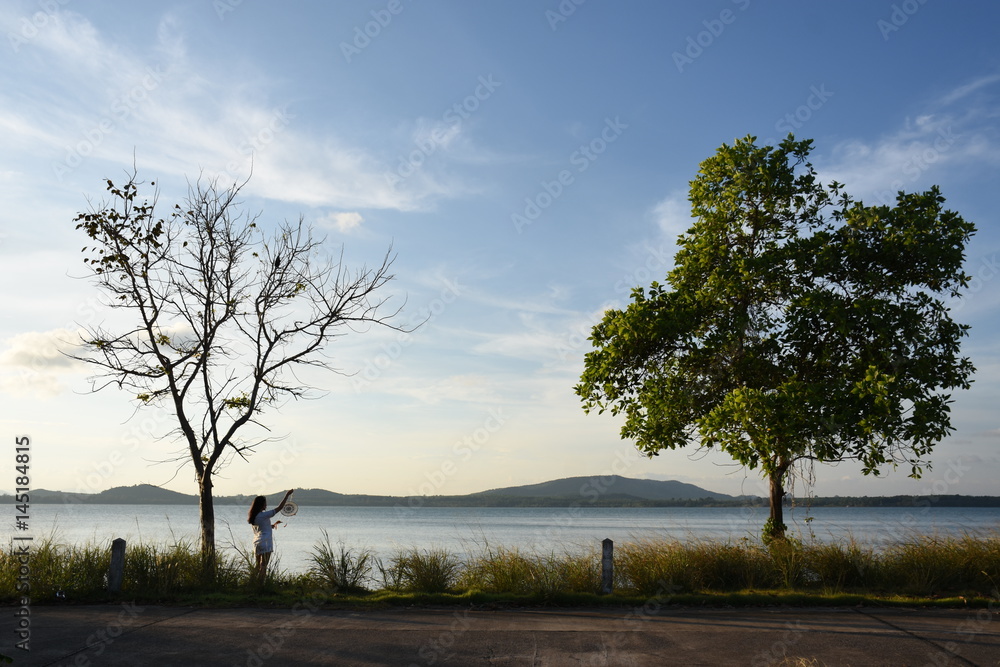 Fototapeta premium Women stand on the Gulf of Thailand at sunset.