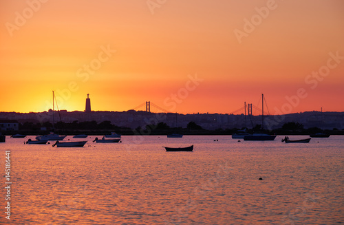 Sunset over the river Tejo, 25th of April Bridge and statue of Christ the King in Lisbon, Portugal