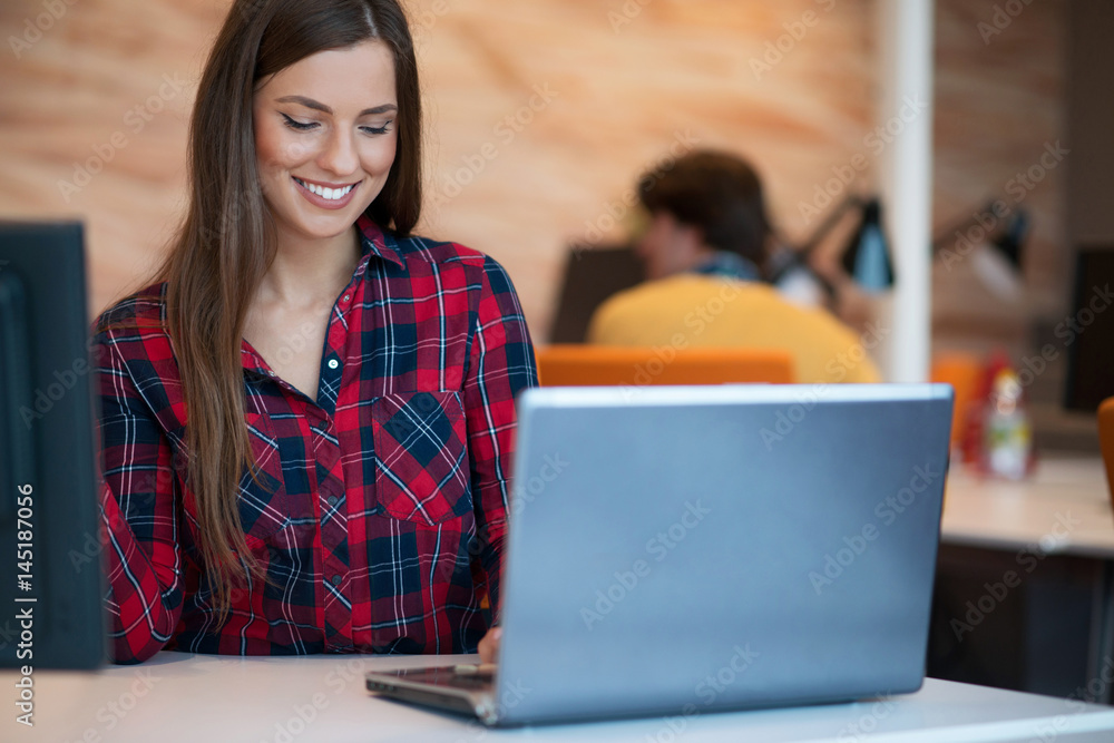 Concentrated at work. Young beautiful woman using her laptop while sitting in chair at her working place Concentrated at work. Young beautiful woman using her laptop while sitting in chair at her working place